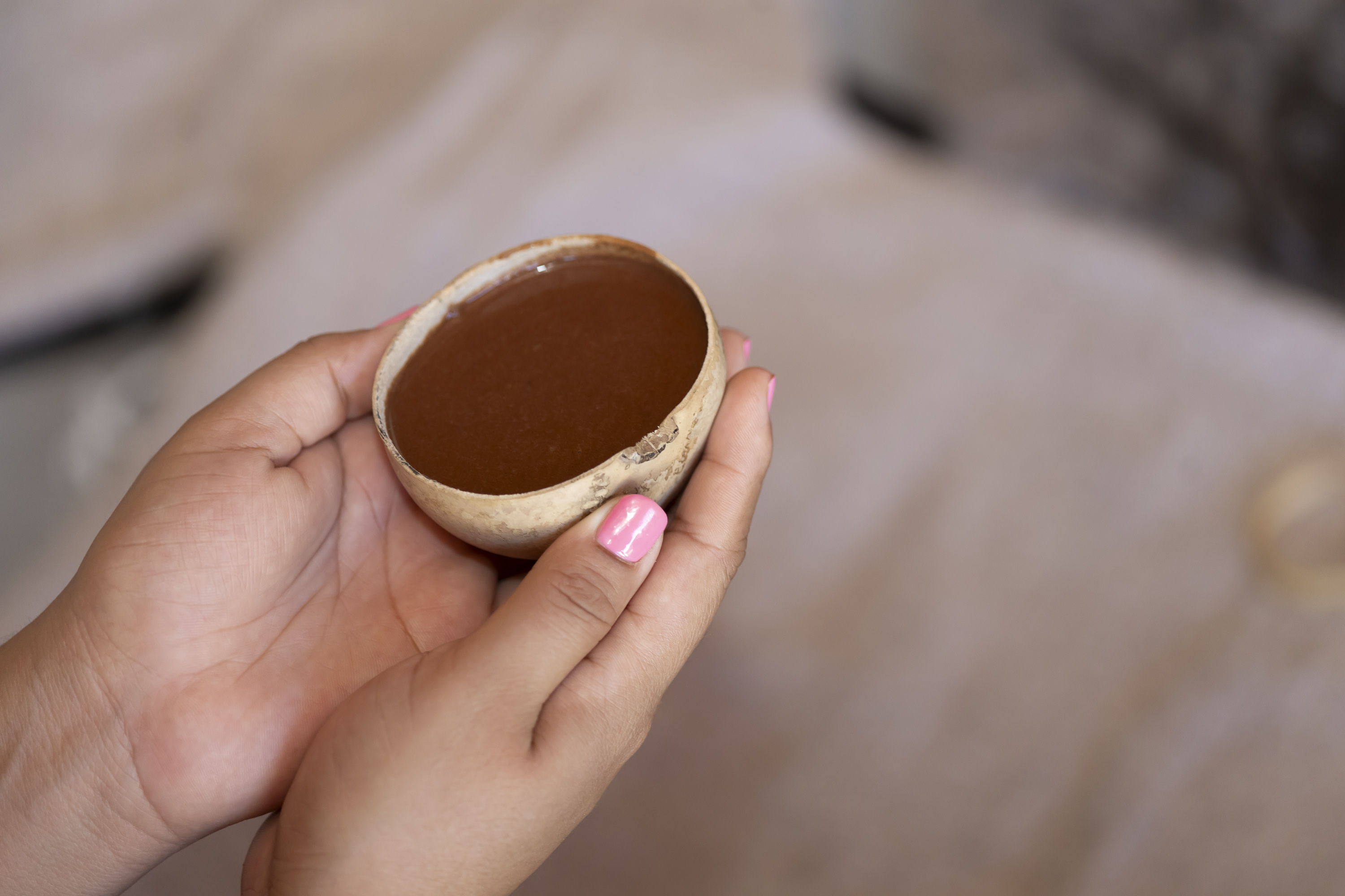 A cup of ceremonial cacao held in hand during an intimate group gathering.