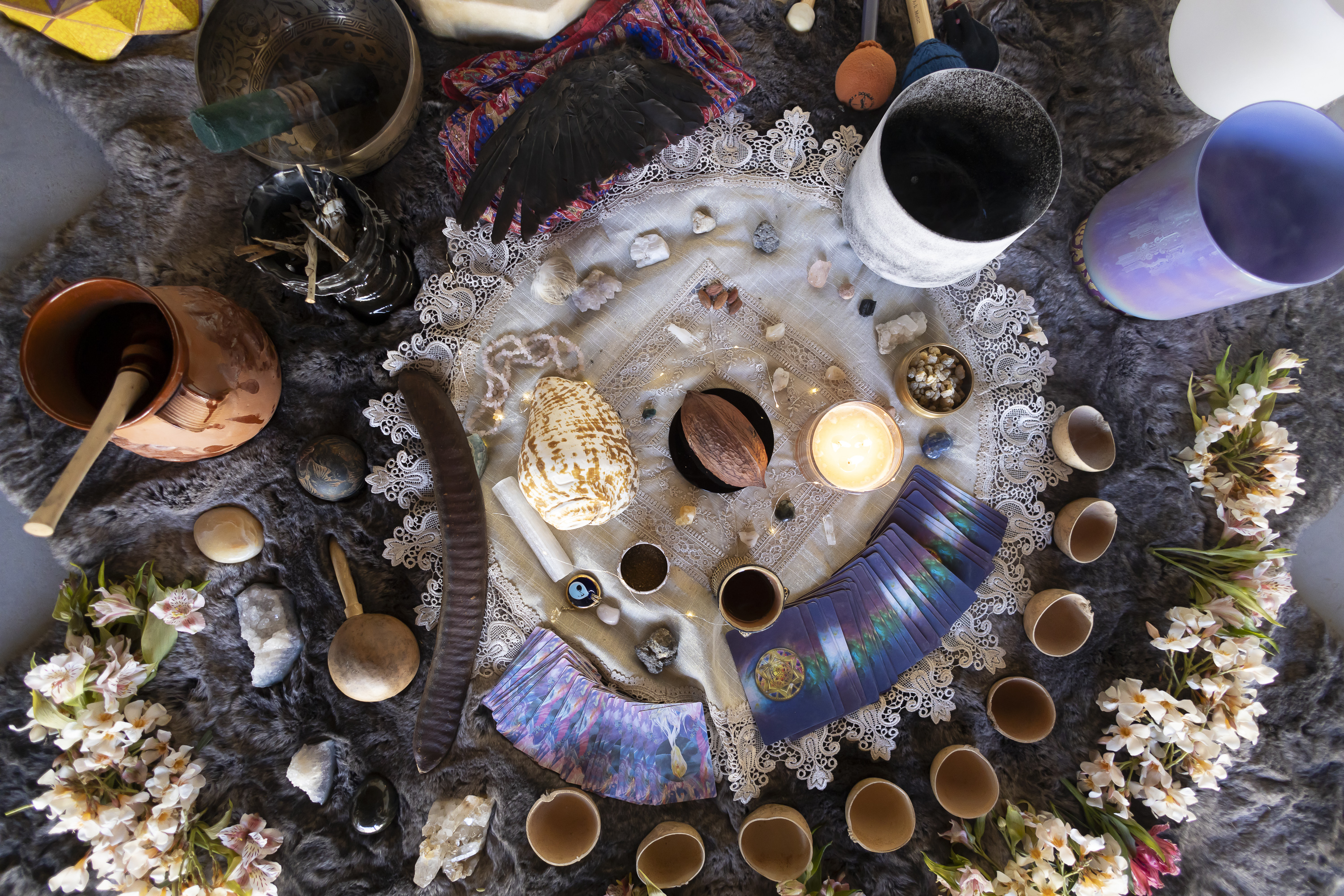 Top-down view of a full ritual setup with cacao, cards, crystals, bowls, and flowers.