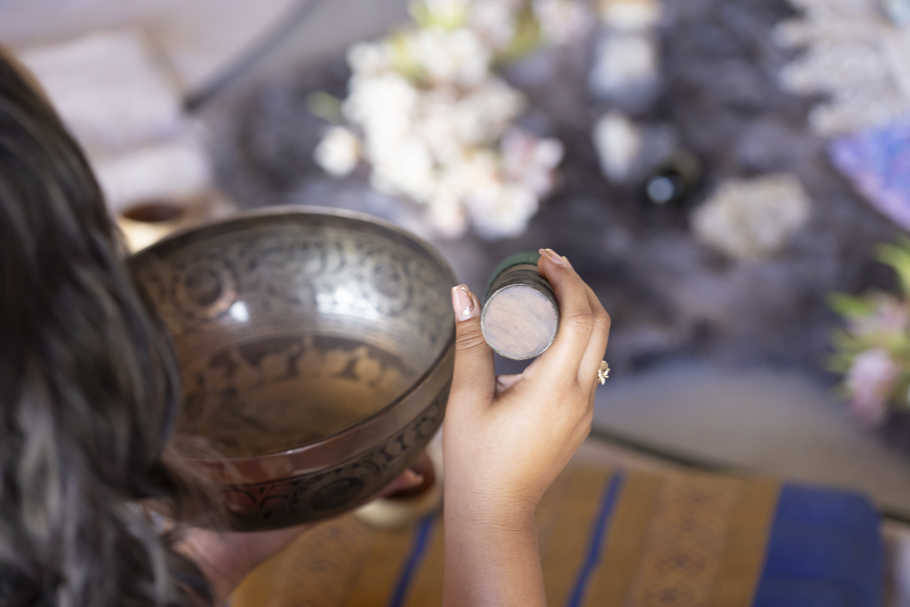 A singing bowl and striker held beside a private sound healing setup.