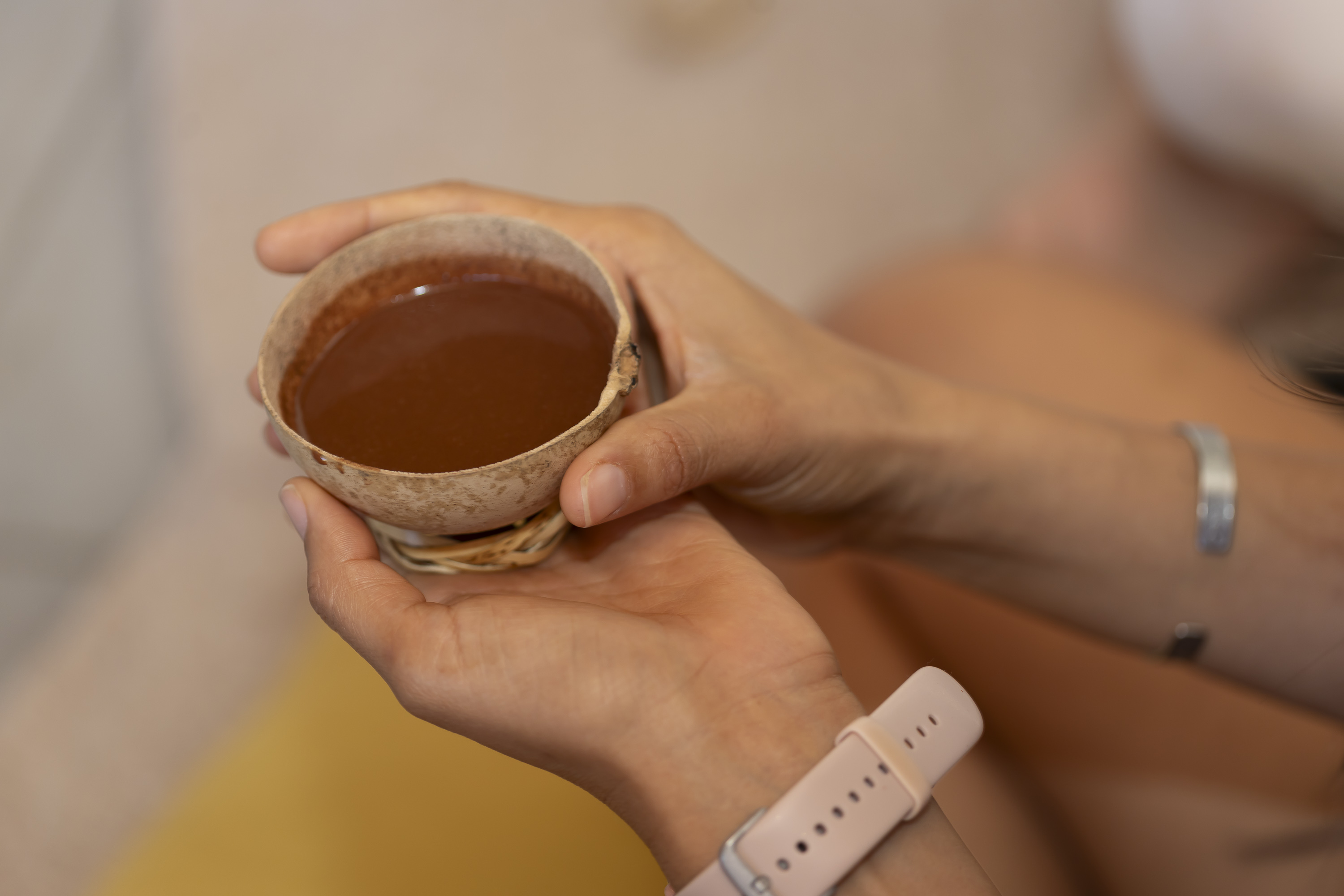 Hands holding a cup of ceremonial cacao during a guided private gathering.